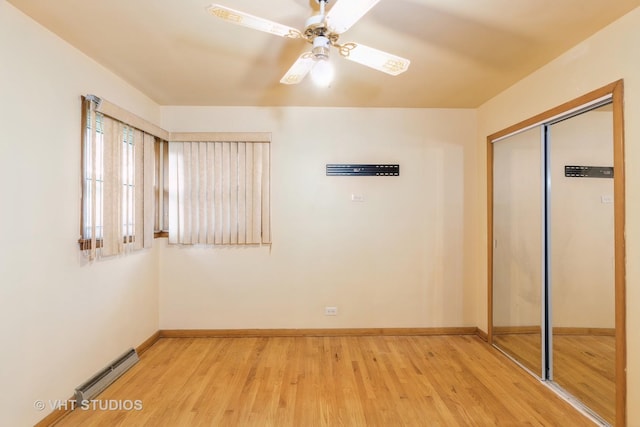 interior space with a baseboard radiator, a closet, baseboards, and light wood finished floors