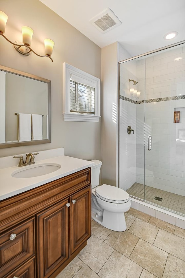 bathroom with vanity, toilet, visible vents, and a stall shower