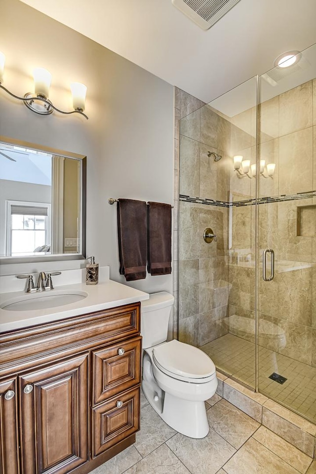 bathroom featuring vanity, a shower stall, toilet, and visible vents