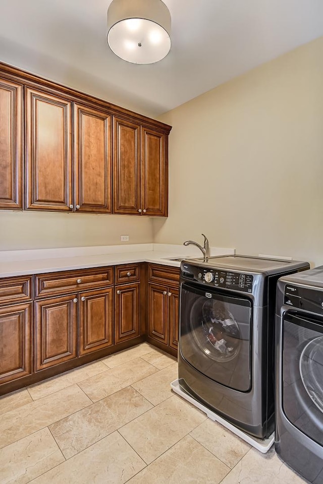 laundry room with a sink, light tile patterned flooring, cabinet space, and washer and clothes dryer