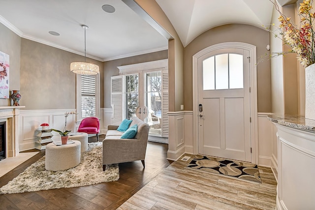 foyer entrance featuring a wainscoted wall, ornamental molding, wood finished floors, a decorative wall, and a premium fireplace