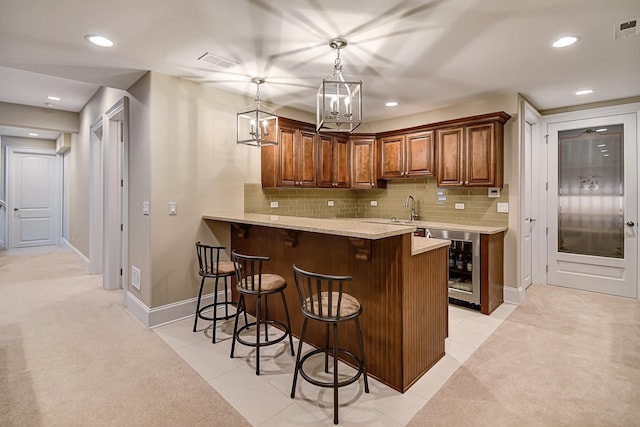 kitchen with a peninsula, a kitchen breakfast bar, beverage cooler, and tasteful backsplash