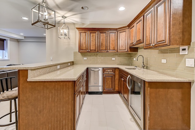 kitchen featuring a breakfast bar, decorative backsplash, a peninsula, brown cabinetry, and a sink