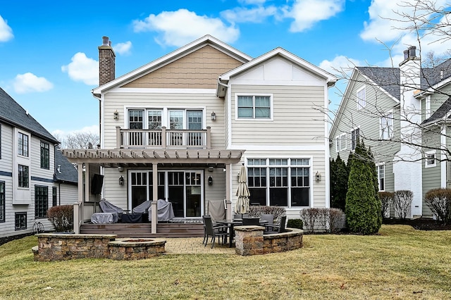 rear view of property featuring a patio area, a yard, a fire pit, and a chimney