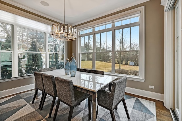 dining room with dark wood finished floors, a chandelier, baseboards, and ornamental molding