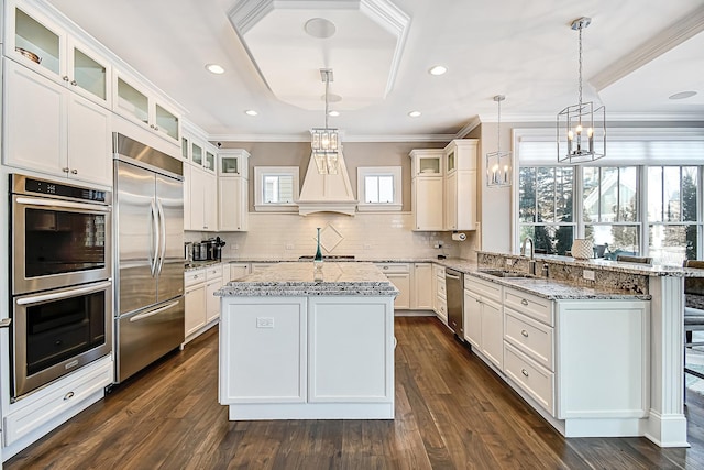 kitchen with crown molding, appliances with stainless steel finishes, a peninsula, white cabinets, and a sink