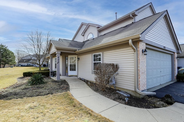 view of front facade with an attached garage, a shingled roof, a front lawn, and brick siding