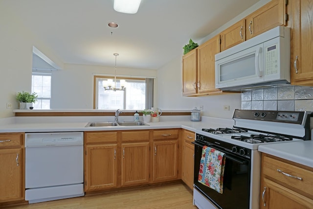 kitchen featuring light countertops, white appliances, a healthy amount of sunlight, and a sink