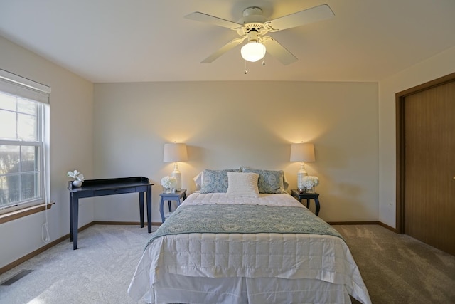 carpeted bedroom featuring a ceiling fan, visible vents, and baseboards