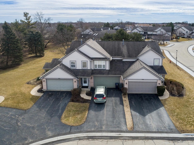 view of front of home with aphalt driveway, a garage, brick siding, a residential view, and a front lawn