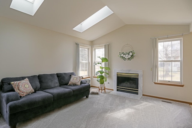 carpeted living area with vaulted ceiling with skylight, a premium fireplace, baseboards, and a wealth of natural light