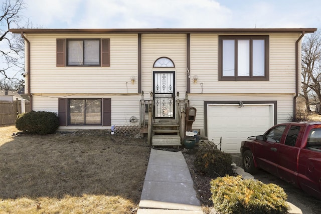 split foyer home with an attached garage and fence