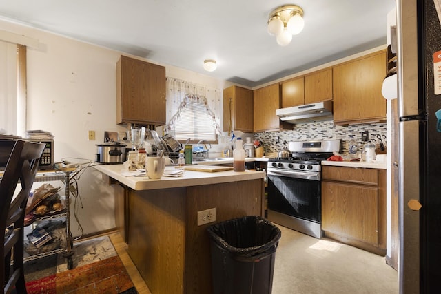 kitchen with under cabinet range hood, light countertops, brown cabinets, decorative backsplash, and gas stove