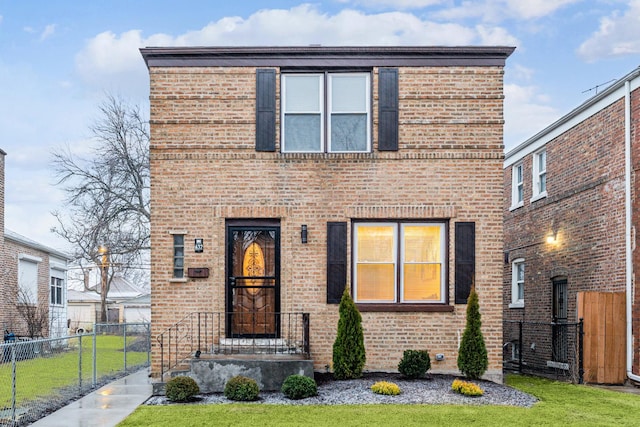 view of front of home featuring brick siding, fence, and a front lawn