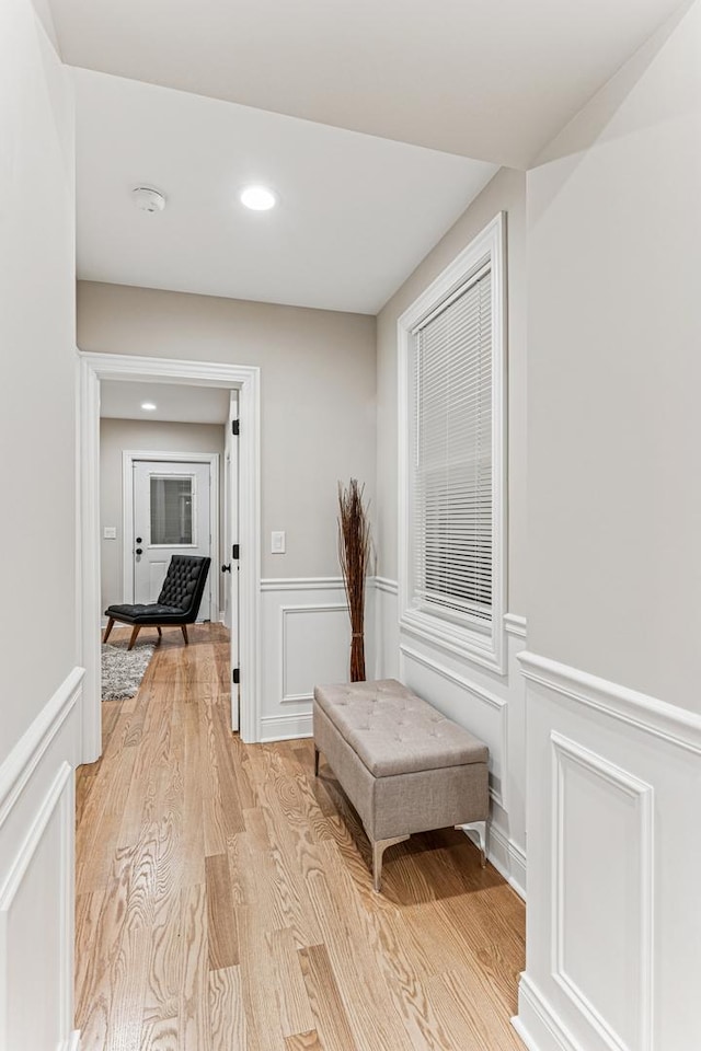 hall featuring recessed lighting, a wainscoted wall, a decorative wall, and light wood finished floors