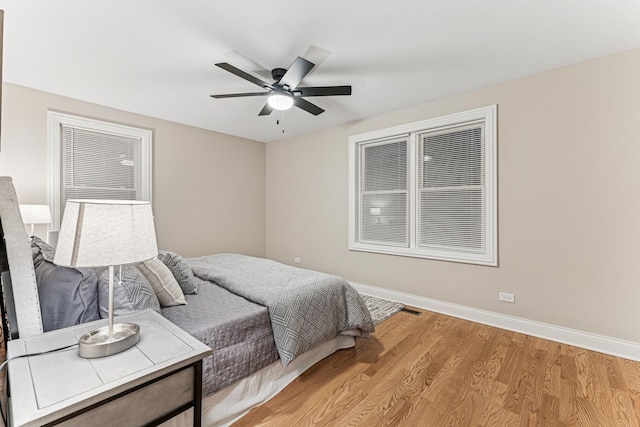 bedroom featuring baseboards, a ceiling fan, visible vents, and light wood-style floors