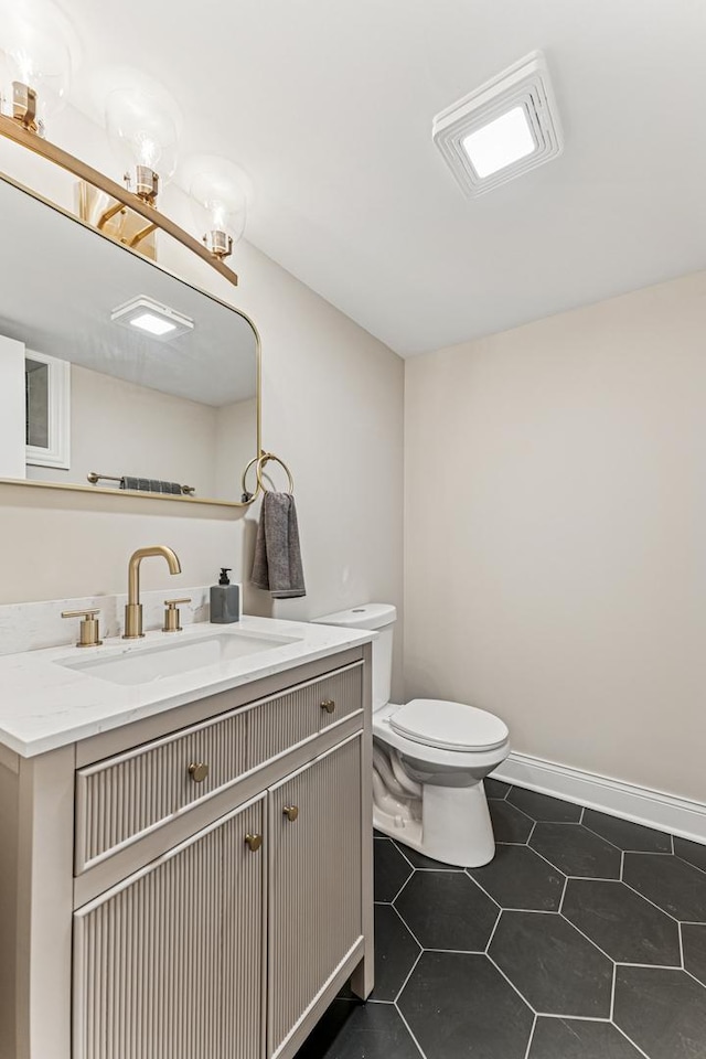 bathroom featuring baseboards, vanity, toilet, and tile patterned floors