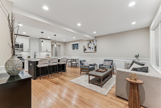 living area with recessed lighting, a wainscoted wall, a decorative wall, and light wood-style flooring