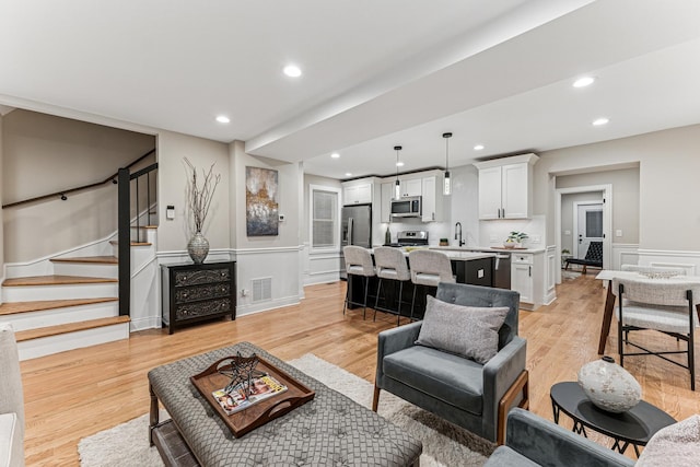 living room featuring visible vents, wainscoting, stairs, light wood-type flooring, and recessed lighting