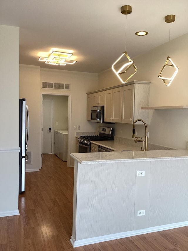 kitchen with washer and clothes dryer, visible vents, light countertops, appliances with stainless steel finishes, and a peninsula