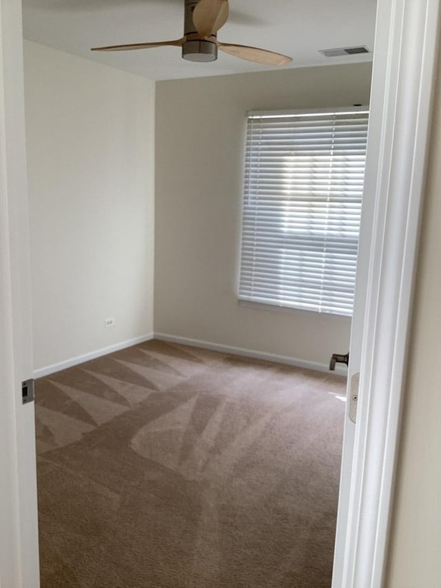 carpeted empty room featuring visible vents, ceiling fan, and baseboards