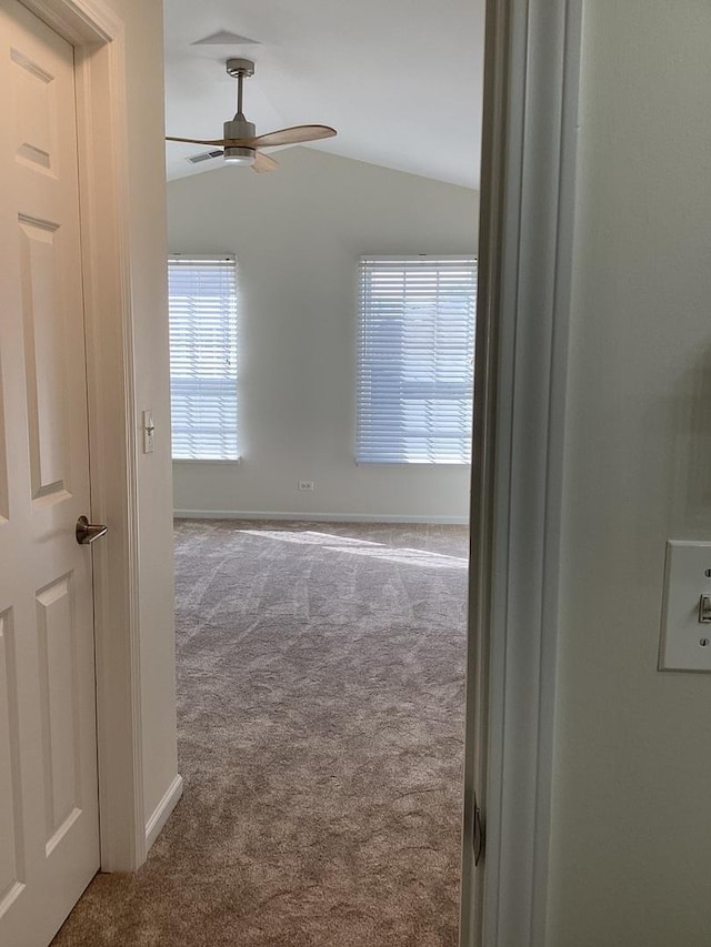 spare room featuring ceiling fan, carpet, baseboards, and vaulted ceiling