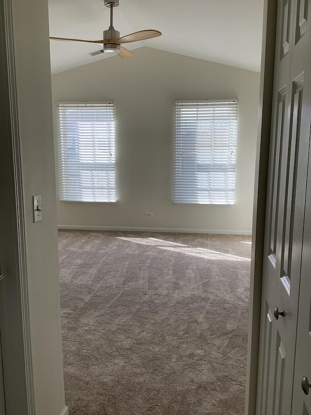 carpeted spare room with lofted ceiling, ceiling fan, and baseboards