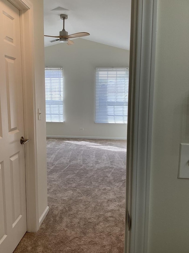 spare room with vaulted ceiling, carpet, a ceiling fan, and baseboards