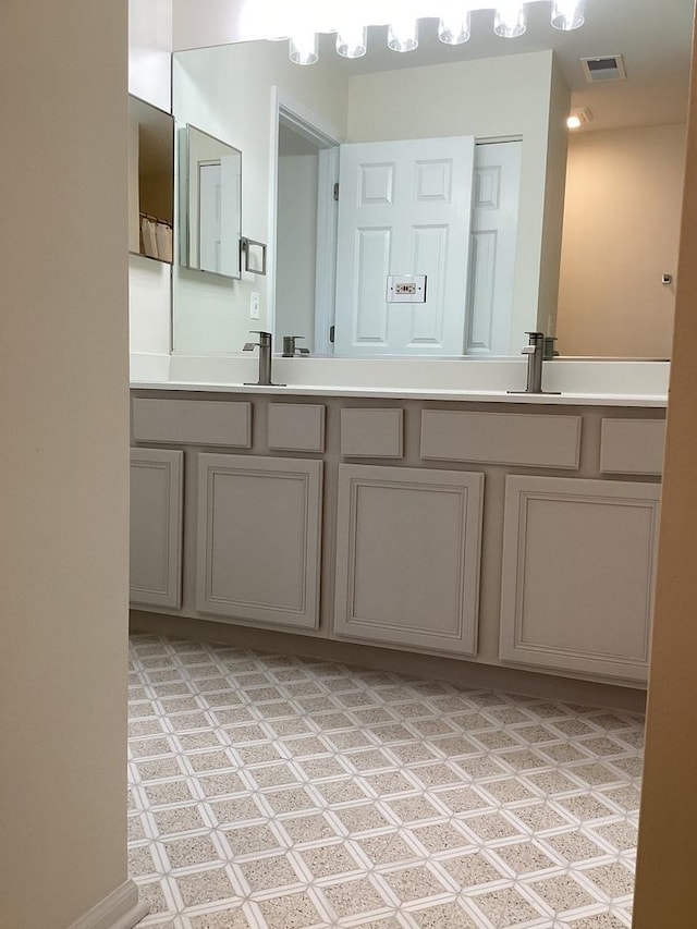 bathroom with double vanity, a sink, and visible vents