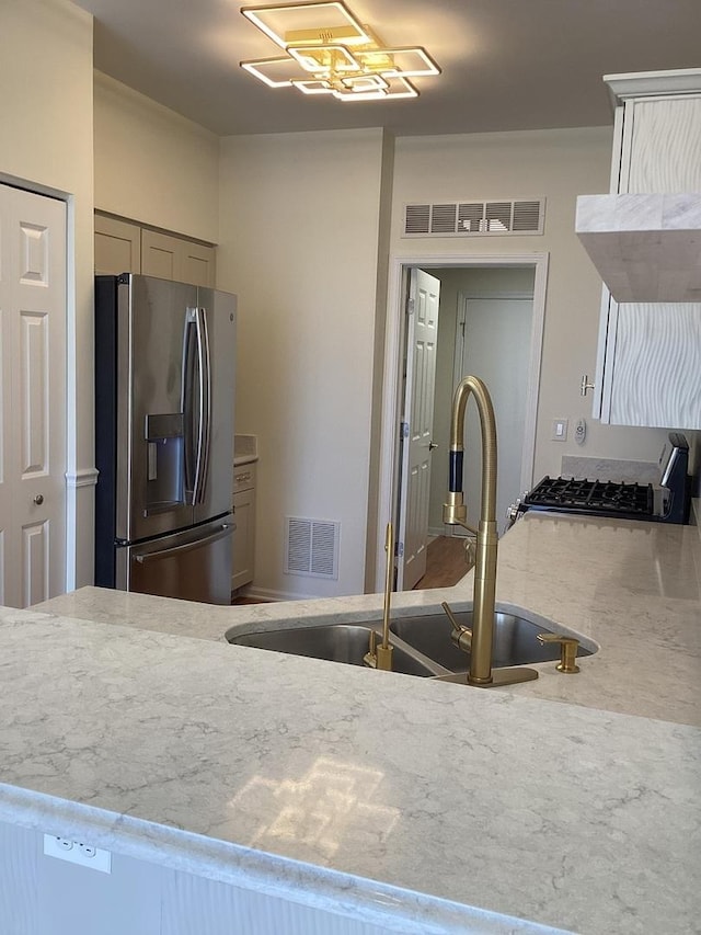 kitchen featuring light stone counters, visible vents, and stainless steel fridge with ice dispenser