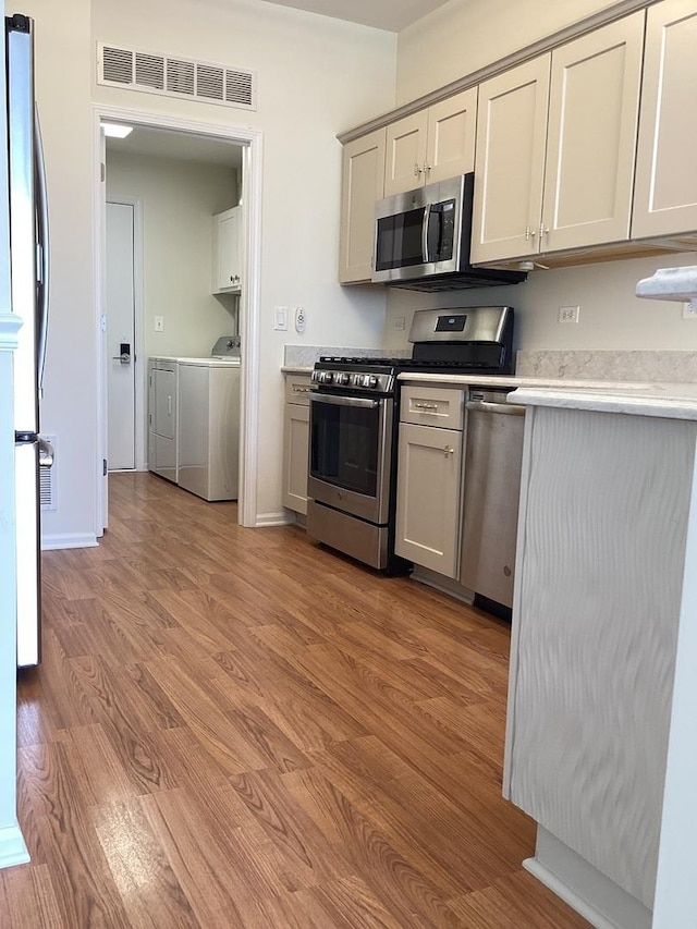 kitchen with light wood-style flooring, visible vents, washer and dryer, light countertops, and appliances with stainless steel finishes