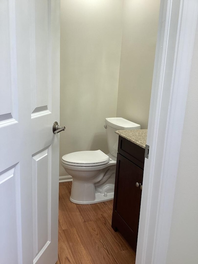 half bath featuring vanity, wood finished floors, and toilet