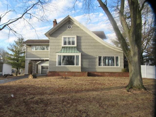 view of front of house with aphalt driveway, a chimney, and a garage