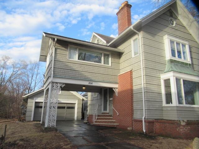 view of front of property featuring driveway, a chimney, and an outdoor structure