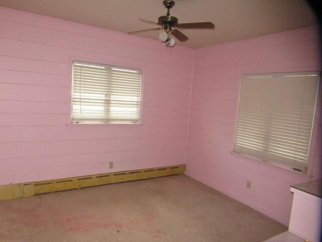 unfurnished room featuring ceiling fan and baseboard heating