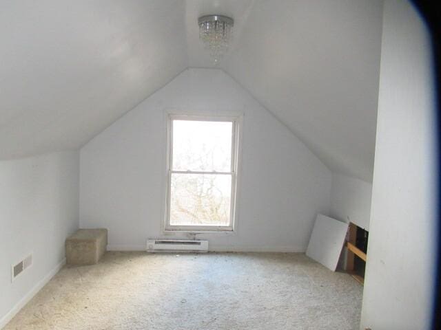 additional living space with carpet, visible vents, a baseboard heating unit, and vaulted ceiling