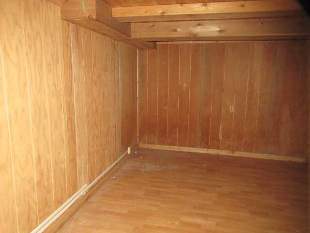 interior space with baseboards, wood finished floors, and wooden walls