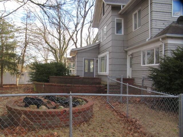 view of side of home featuring fence and french doors