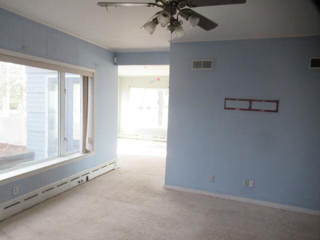 unfurnished room featuring ceiling fan, a baseboard radiator, carpet flooring, visible vents, and baseboards