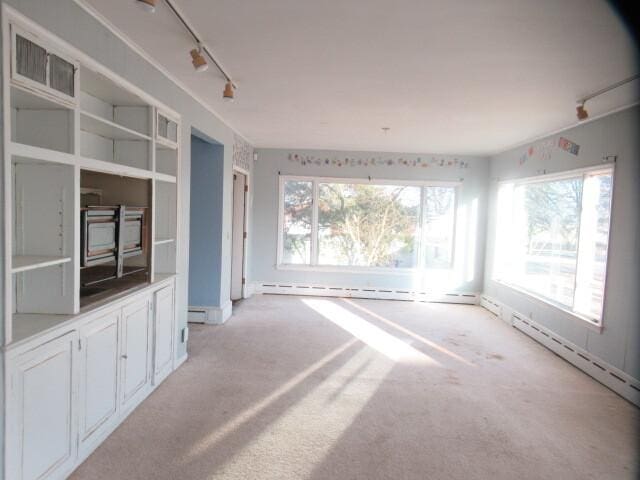 unfurnished room featuring a baseboard heating unit, visible vents, light carpet, and track lighting