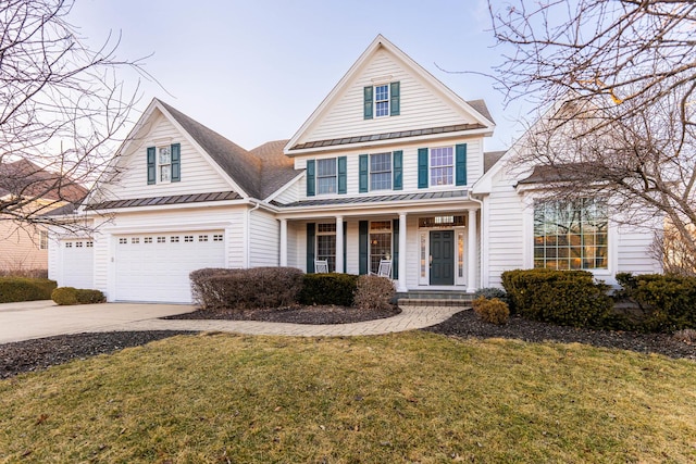 traditional home with a front yard, driveway, a standing seam roof, a garage, and metal roof