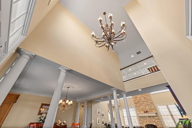 room details featuring visible vents, ornamental molding, decorative columns, a fireplace, and a notable chandelier