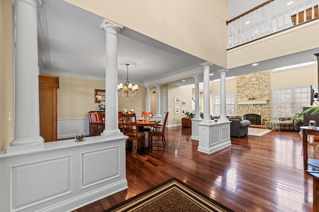 living area with a stone fireplace, crown molding, and ornate columns