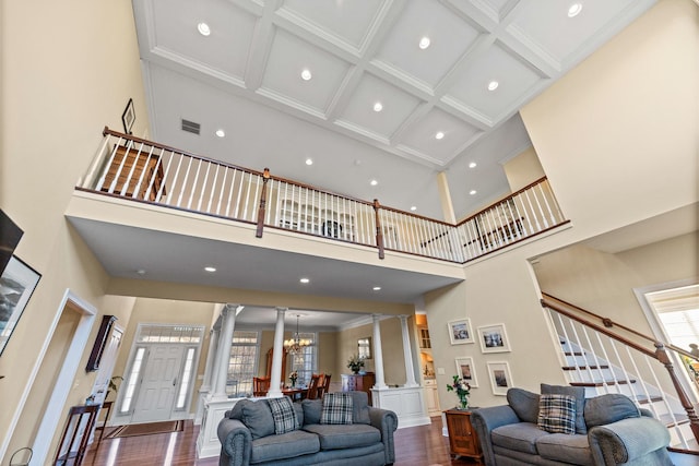 living area with crown molding, dark wood finished floors, stairway, decorative columns, and a notable chandelier