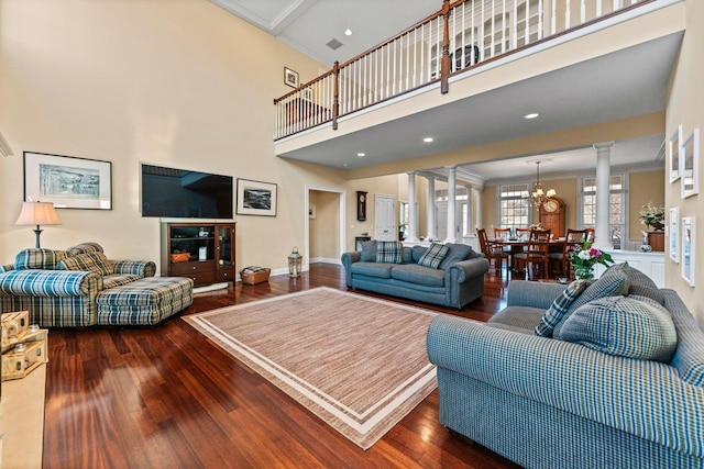 living room featuring crown molding, baseboards, a chandelier, wood finished floors, and ornate columns