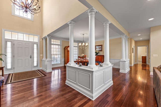 foyer with dark wood finished floors, decorative columns, and a wealth of natural light