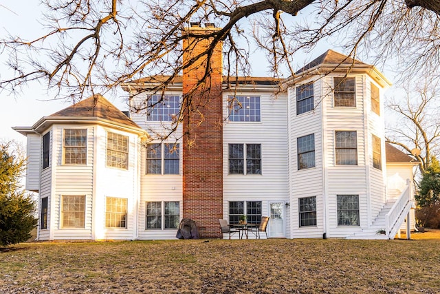 back of property with a patio, a lawn, and a chimney