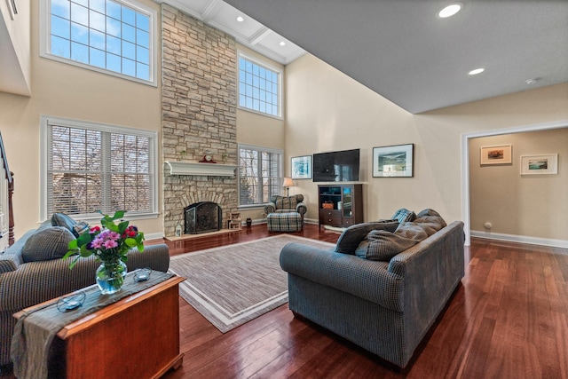 living room featuring baseboards, a stone fireplace, recessed lighting, a high ceiling, and wood-type flooring