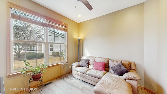 living area featuring a ceiling fan, baseboards, visible vents, and wood finished floors