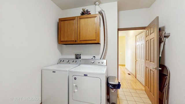 washroom with cabinet space, light tile patterned floors, and washing machine and clothes dryer